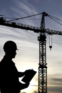 person in hardhat in front of crane