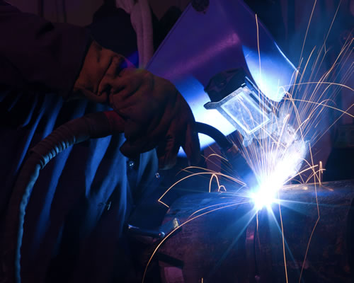 Dramatic blue-lit MIG welding close